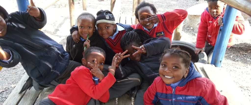 Children smiling and playing outdoors at a school playground, representing school ratings and student happiness in South Africa.