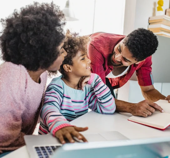 Young girl with her parents engaging in a school activity or homework at a table, promoting education and family involvement in student success.